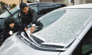 車のフロントガラスに積もった雪を払う親子＝浜松市東区で